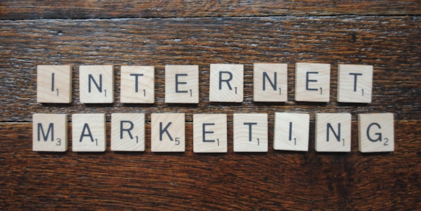 Wooden Scrabble tiles spell out the words 'INTERNET MARKETING' on a textured wooden surface.