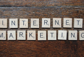 Wooden Scrabble tiles spell out the words 'INTERNET MARKETING' on a textured wooden surface.