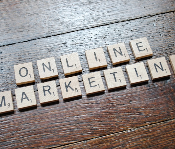 Scrabble tiles arranged to spell 'ONLINE MARKETING' on a wooden table with a textured surface.